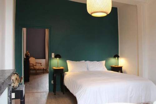une chambre avec un grand lit blanc et un mur vert dans l'établissement Marceau - view on Cathedral and Place des Epars, à Chartres