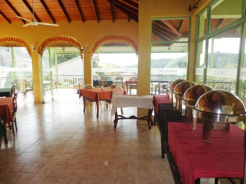 a dining room with tables and chairs and windows at Amanda Hills in Kandy