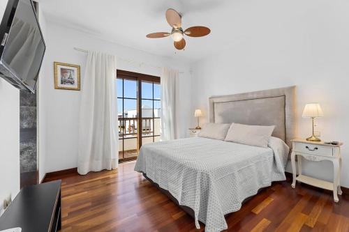 a white bedroom with a bed and a television at Villa Nica in Costa Teguise