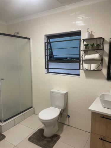La salle de bains est pourvue de toilettes, d'un lavabo et d'une fenêtre. dans l'établissement Masana at Homely Escape, à Phalaborwa