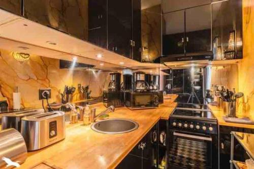 une grande cuisine avec des comptoirs en bois et des armoires noires dans l'établissement Sublime appartement Bordeaux Hôtel de Ville, à Bordeaux