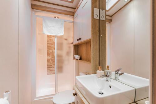 a bathroom with a sink and a toilet at The Pines - Norfolk Cottage Agency in Weybourne