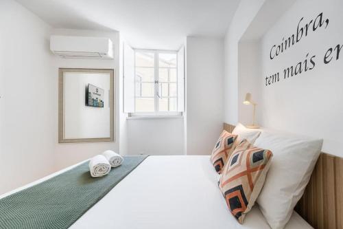 biała sypialnia z dużym łóżkiem i lustrem w obiekcie A charming stay near Paço das Escolas w mieście Coimbra