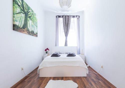 a white bedroom with a bed and a window at Märzstraße Apartment in Vienna