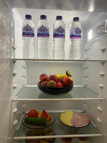 a refrigerator filled with bottles of water and a bowl of fruit at Pinchbeck B&B in Pinchbeck