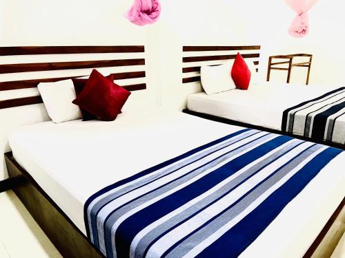 two beds in a room with red and blue pillows at Geethani Tourists Home in Polonnaruwa