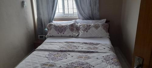 Lovely 2-Bed Apartment in Kaosa في Kasoa: غرفة نوم صغيرة مع سرير مع الوسائد ونافذة