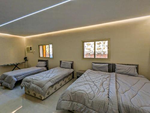 a bedroom with two beds and two windows at Madina Luxe Apartments - 7 minutes to Haram by Car - Mount Uhud Views - Free Parking - Kitchen in Al Madinah