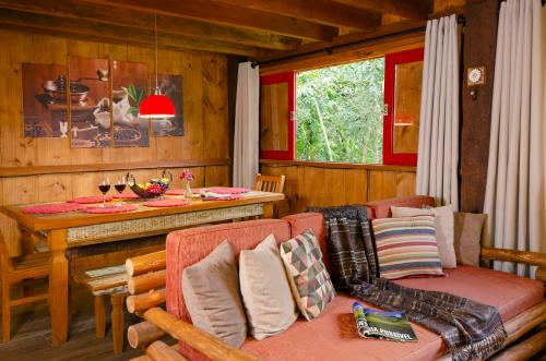 a living room with a couch and a table in a cabin at Pousada Fazenda Rio das Pedras in Visconde De Maua