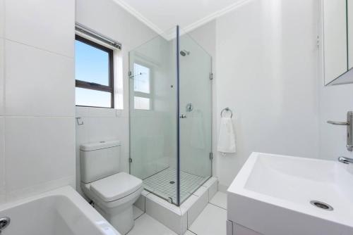 a white bathroom with a toilet and a glass shower at Captivating 2-Bed Apartment in Sandton in Sandton