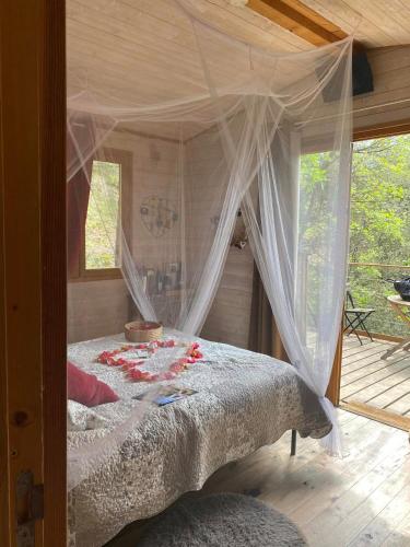 - une chambre avec un lit à baldaquin et une fenêtre dans l'établissement La cabane des amoureux, à Barjols