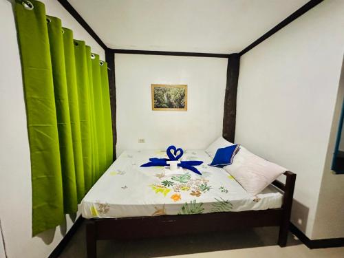 Un dormitorio con una cama con una cinta azul. en Siargao Zita's Garden Inn, en General Luna