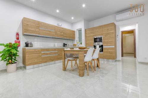 een keuken met houten kasten en een tafel en stoelen bij Modern fully Equipped 1BR home in St Julians by 360 Estates in St Julian's