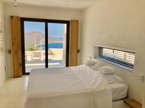 een witte slaapkamer met een bed en uitzicht op de oceaan bij Mr. Bliss in Avlemonas