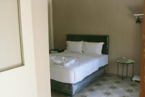 1 dormitorio con 1 cama grande con sábanas blancas en Lamina Repoq Hiils, en Kuta Lombok