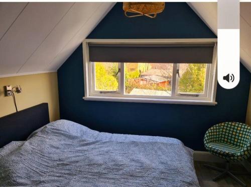a bedroom with a blue wall and a window at Een heerlijke vakantiewoning aan de Zeeuwse kust in Breskens