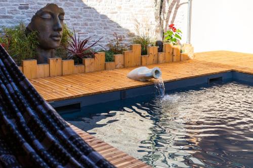 uma piscina com uma estátua de uma cabeça na água em Gites du Fort au Prince em Eymet