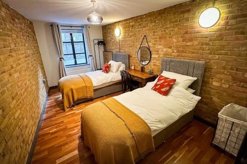 a bedroom with two beds and a brick wall at Luxury Warehouse Conversion - Shoreditch in London