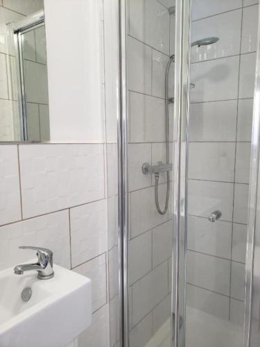 a bathroom with a shower and a sink and a mirror at Tollgate Drive in Southall