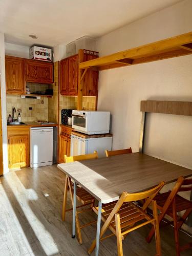 Il comprend une cuisine avec une table et des chaises en bois. dans l'établissement La Foux d'Allos, coquet studio au pied des pistes, à La Foux