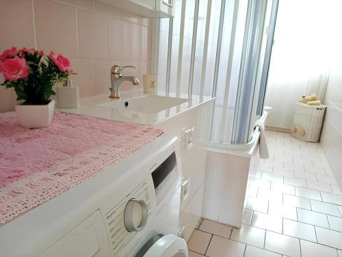 biała łazienka z umywalką i pralką w obiekcie La casa dei fiori we Florencji
