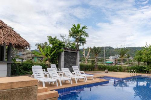 - un groupe de chaises blanches installées à côté de la piscine dans l'établissement OYO 1046 Noppharat Resort, à Ao Nang Beach