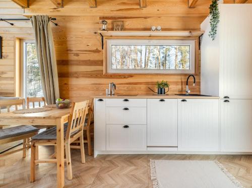 a kitchen with white cabinets and a table and a window at Warmia Forest Kobułty 