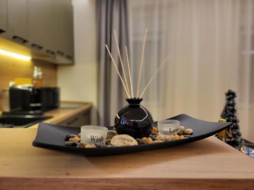 une assiette avec un vase et deux tasses sur une table dans l'établissement Duga Apartmani 1, à Subotica