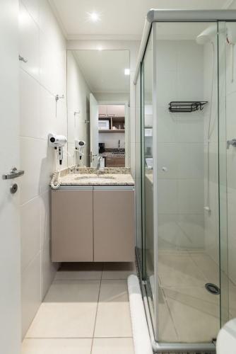 a bathroom with a sink and a glass shower at Jaques Pilon | Studio Centro | Perto de Tudo in São Paulo