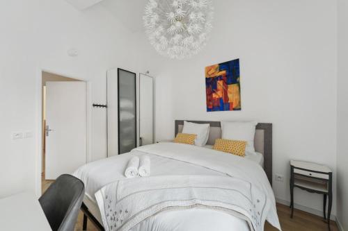 a bedroom with a large white bed with a chandelier at Chic apart terrace garden parking in Asnières-sur-Seine