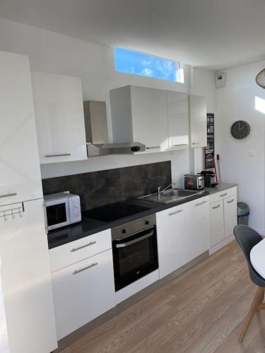 une cuisine blanche avec un évier et un micro-ondes dans l'établissement 