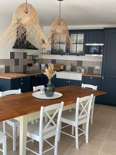 - une cuisine avec une table en bois et des chaises blanches dans l'établissement Agréable maison de ville en bord de mer, à Royan