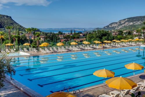 a large swimming pool with yellow umbrellas and chairs at Poiano Garda Resort Appartamenti in Garda