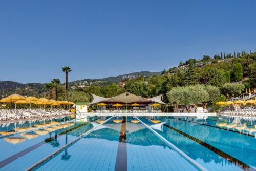 a large swimming pool with chairs and umbrellas at Poiano Garda Resort Appartamenti in Garda