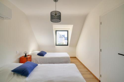 deux lits dans une petite pièce avec une fenêtre dans l'établissement Maison en bord de mer pour 4, à Kérity, à Penmarcʼh