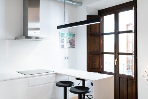 una cocina con encimera blanca y taburetes en Apartamento Gracia, en Granada