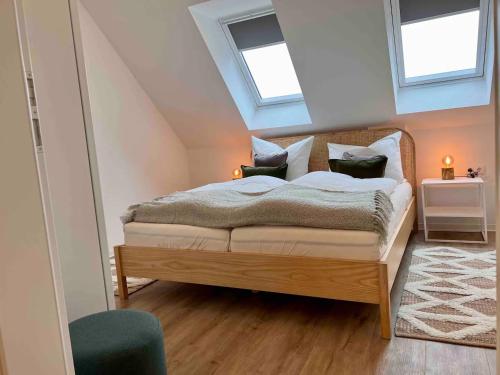 a bedroom with a bed in the attic with two windows at Fewo Wolke in Menslage