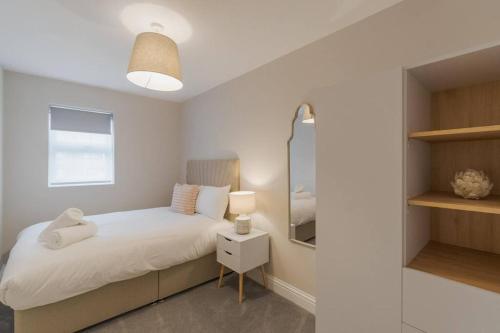 a white bedroom with a bed and a mirror at Cozy 2 Bed Retreat - Allocated Parking in Windsor