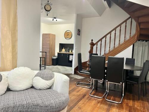 un salon avec un canapé et une table avec des chaises dans l'établissement La Ribaudière Maison de ville à 5 min Futuroscope, à Chasseneuil-du-Poitou