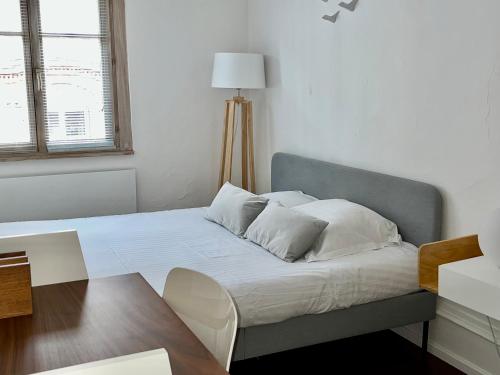 un lit avec des draps blancs et des oreillers dans une chambre dans l'établissement Le grand rue, à Strasbourg