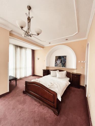 Un dormitorio con una cama grande y una lámpara de araña. en Pensiunea Curtea Bavareza, en Târgu Mureș