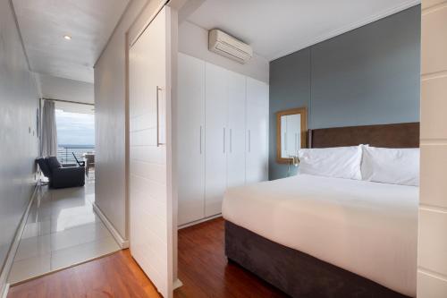 a bedroom with a large white bed and a balcony at Point Waterfront Apartments in Durban