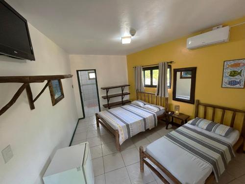 a bedroom with two beds and a flat screen tv at Pousada Beleza Pura na Praia da Ferrugem in Garopaba