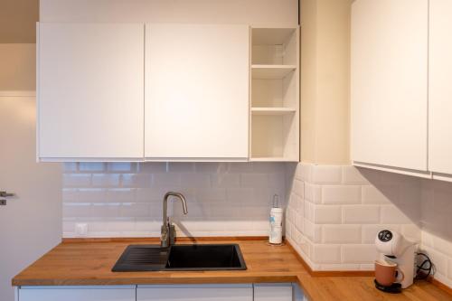 eine Küche mit weißen Schränken und einem Waschbecken in der Unterkunft Design 1BDR Apartment near City Center in Sofia