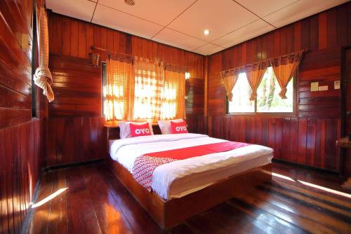 a bedroom with wooden walls and a bed with red pillows at OYO 476 Ban Rimnam Resort in Nakhon Pathom
