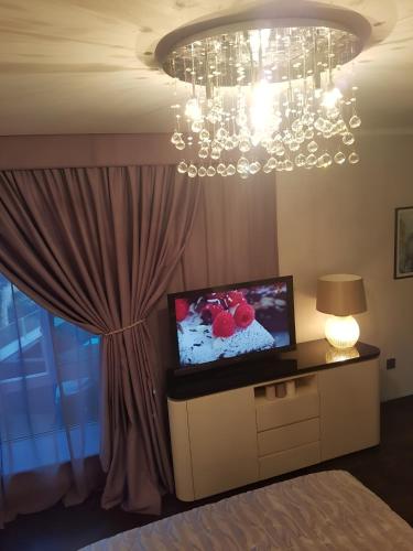 a bedroom with a chandelier and a bed with a television at Top-notch apartment with sea view, bbq and Jacuzzi in St Julian's