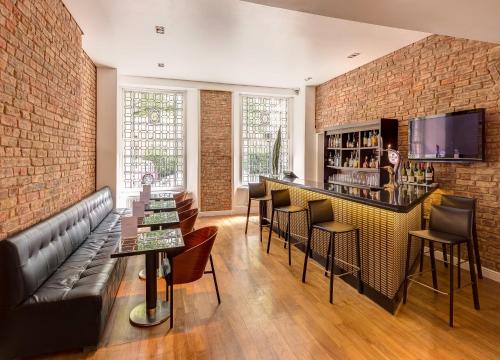 a bar with a couch and chairs and a brick wall at Caesar Hotel in London