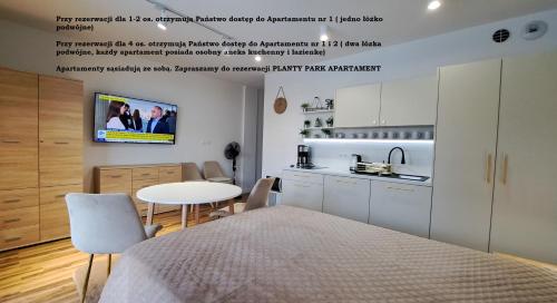 Habitación con cama, mesa y cocina. en Planty Park Apartament en Nowy Sącz