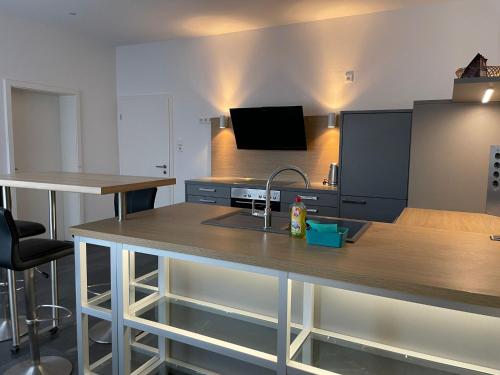 una cucina con piano di lavoro, lavandino e TV di M&M Apartment Düsseldorf a Neuss