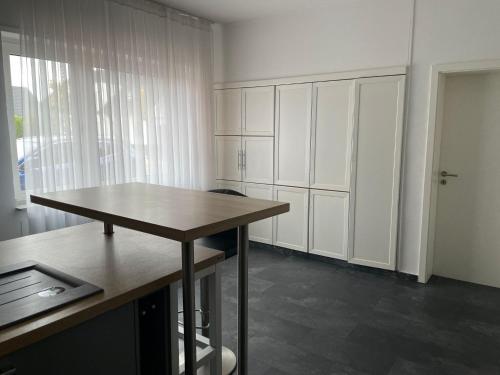 a kitchen with white cabinets and a wooden table at M&M Apartment Düsseldorf in Neuss
